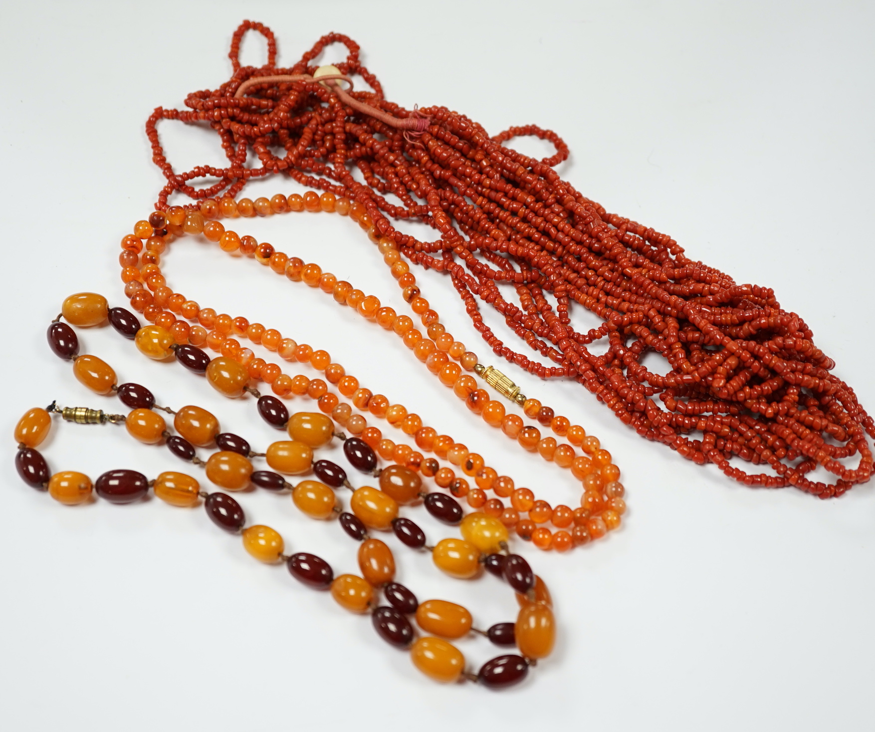 A single strand amber and simulated cherry amber bead necklace, 72cm, gross weight 33 grams, together with two other necklaces including agate bead.
